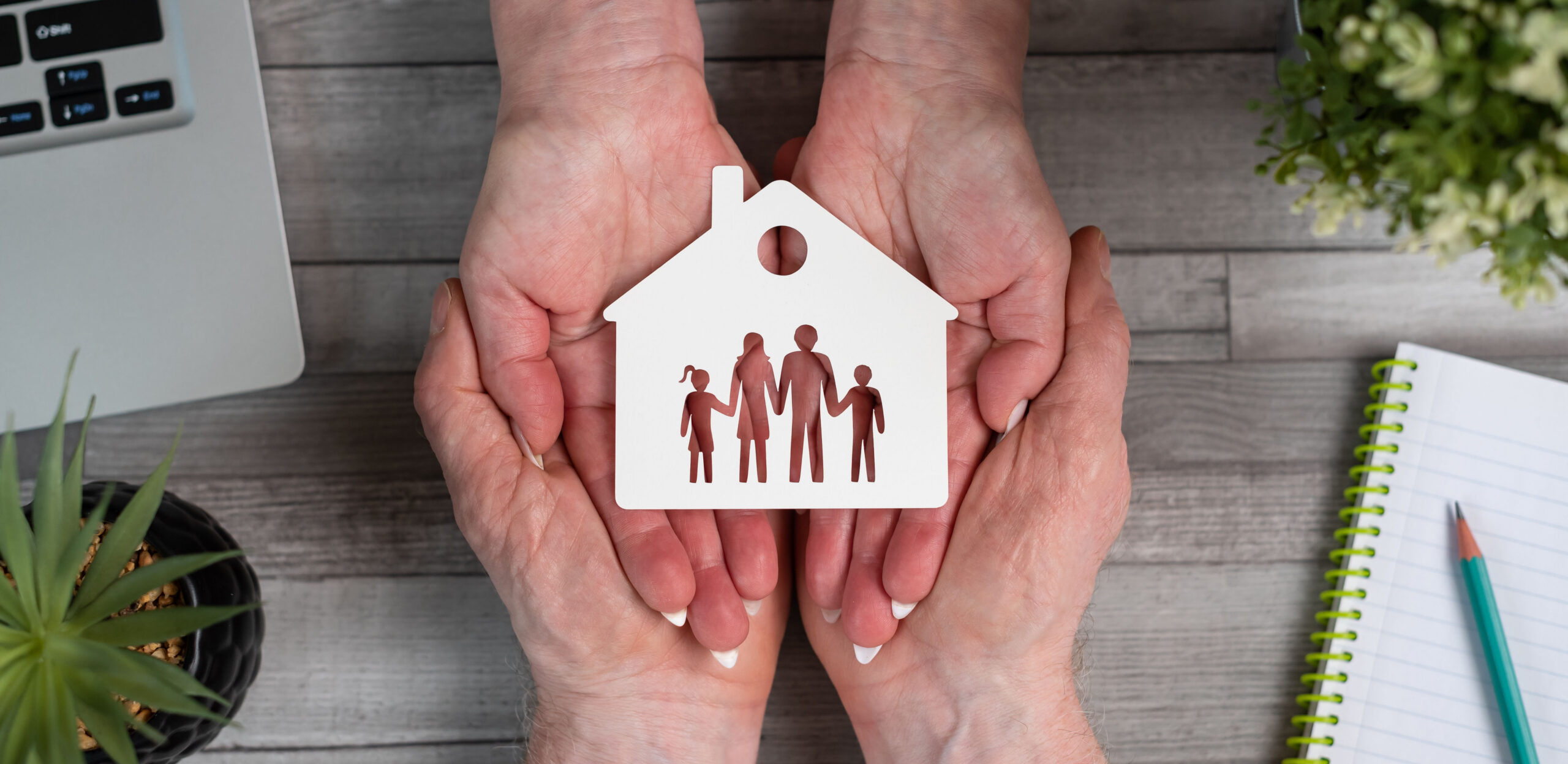 Concept of family and house insurance with paper house and family in hands